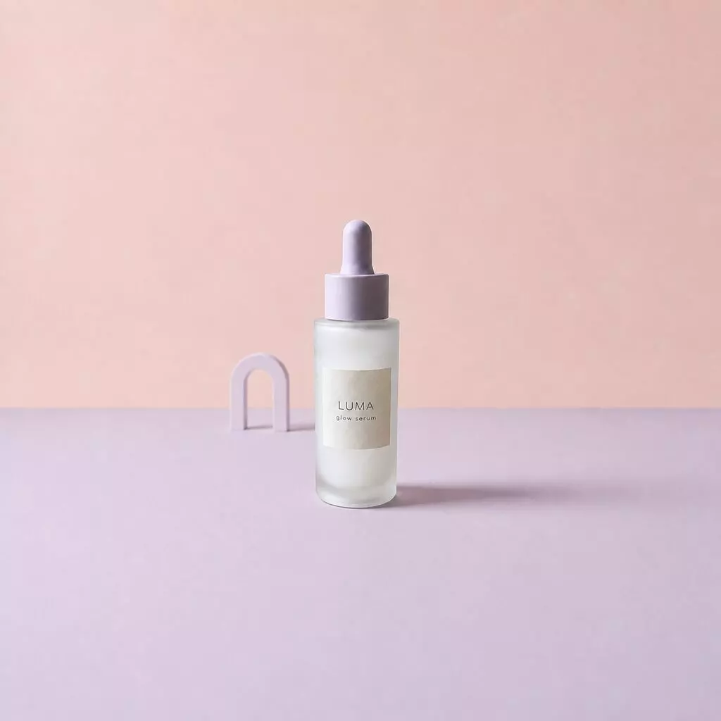 The same serum bottle on a minimal pastel set with a soft shadow